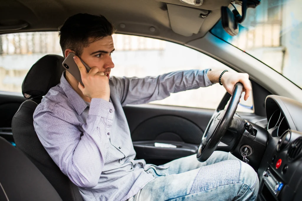 young man talking phone while driving his car